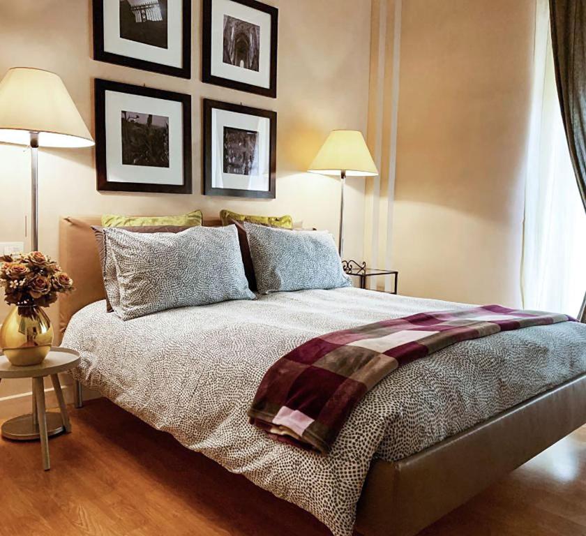 a bedroom with a large bed with two lamps and pictures on the wall at B&B La Littorina - Parcheggio Privato in Foligno