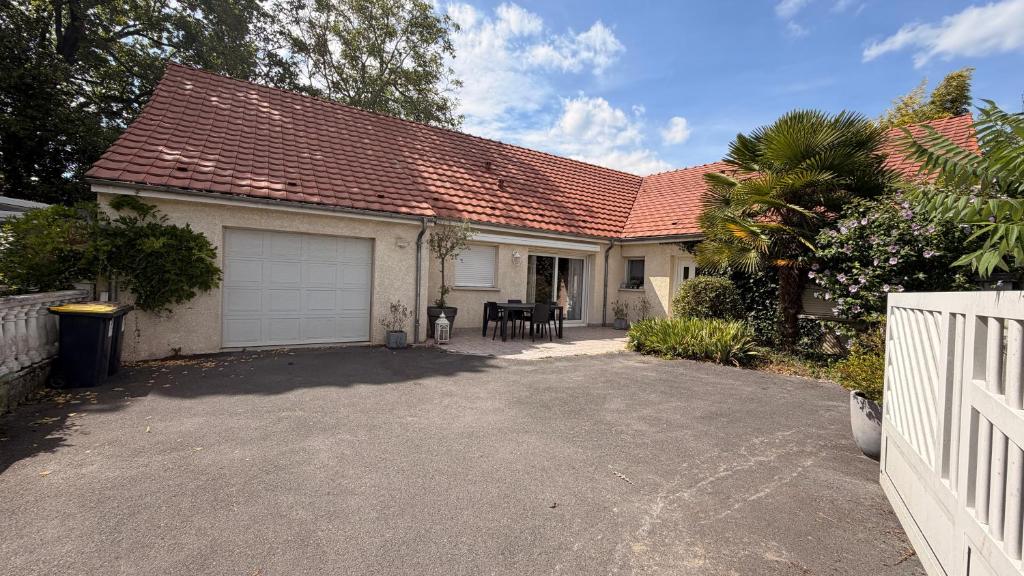a house with a garage and a white fence at Chez Delphine in Damery