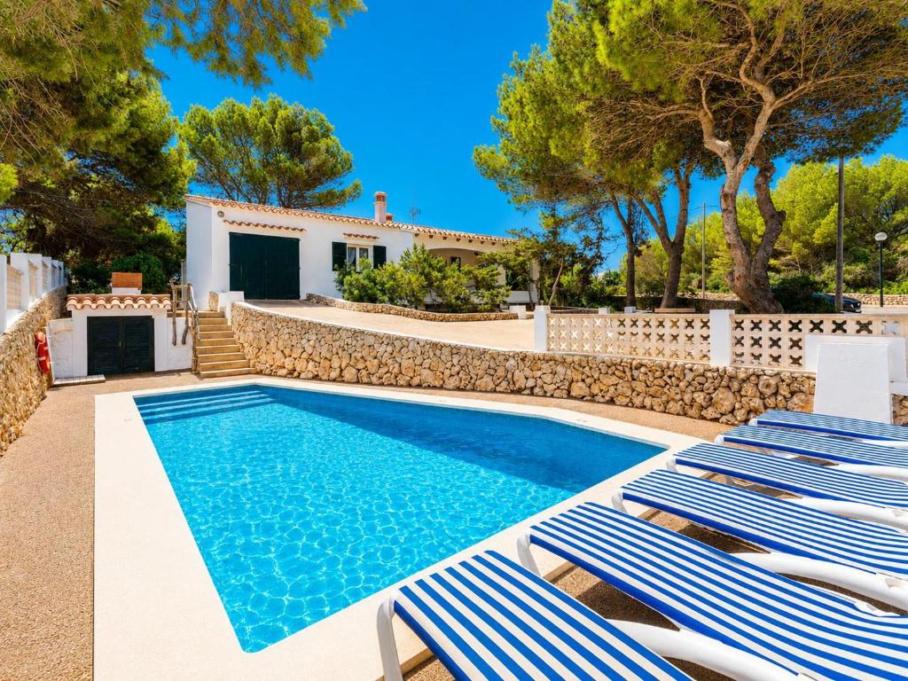 a swimming pool with two lounge chairs and a house at Villa Trepuco Dos in Punta Prima