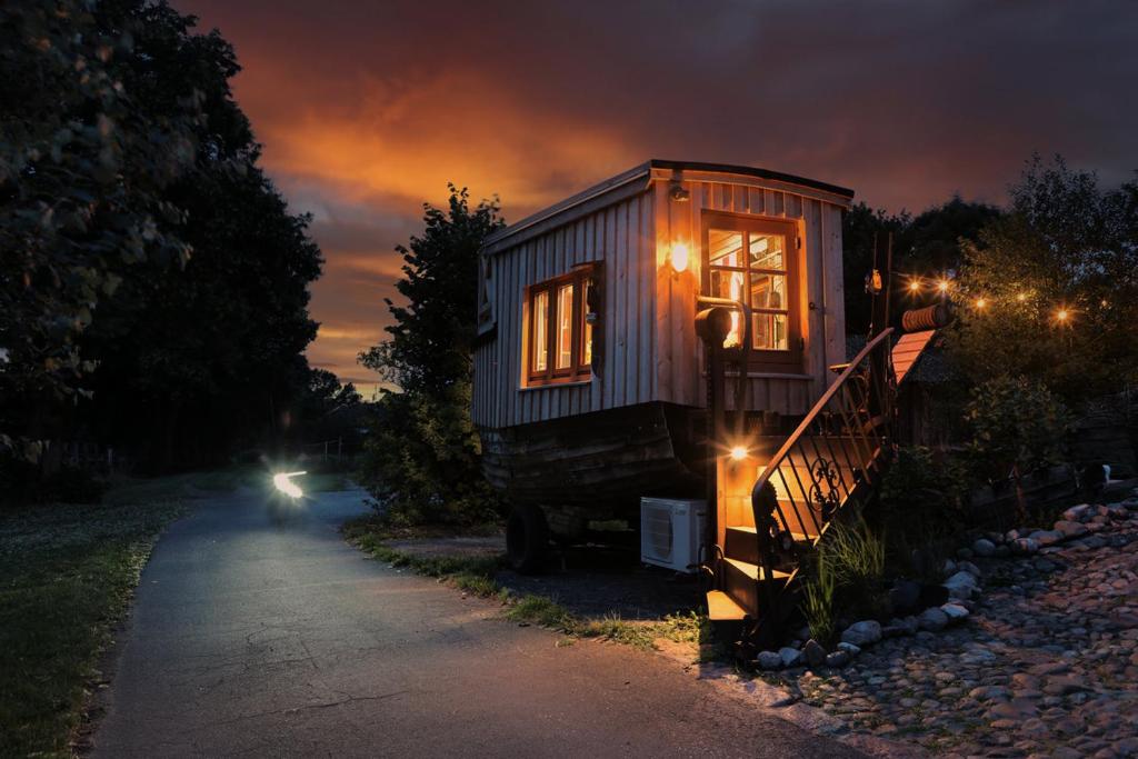 a tiny house with lights on the side of a road at Tiny Boat Berta in Ottenbüttel