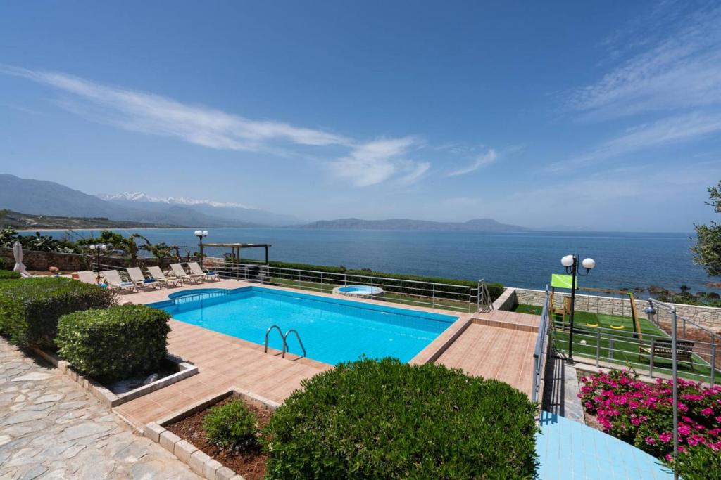 a swimming pool with a view of the ocean at Beachfront Family Villa Katerina with Private pool, Playground, BBQ & Amazing Sea Views! in Petres