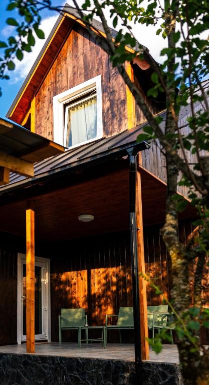 a house with two green chairs on the porch at Casa de Lângă Mesteceni in Dealu Negru