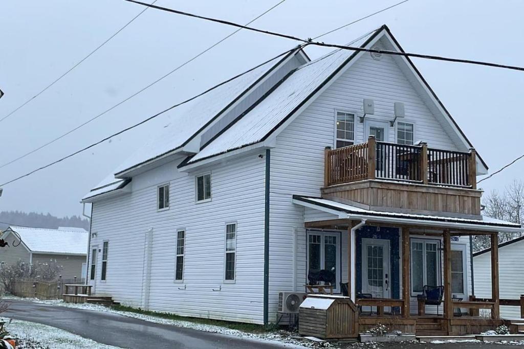 a white house with a balcony on top of it at Fin's Studio, Fundy Park in Alma