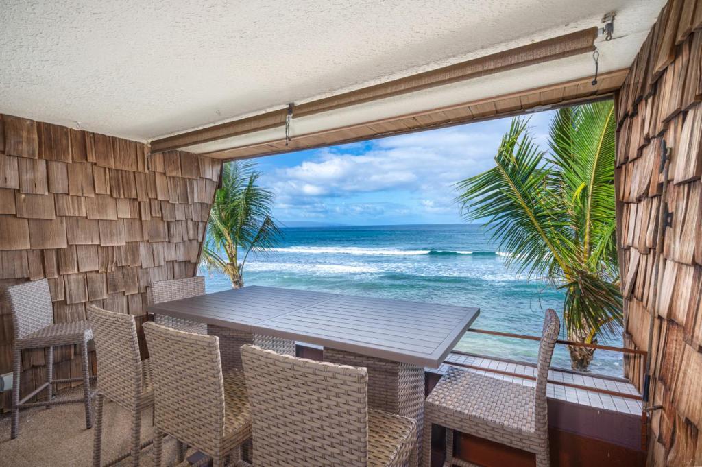 a table and chairs on a balcony with the ocean at Modern-Rustic Beach Renovation Direct Oceanfront Penthouse in Kahana