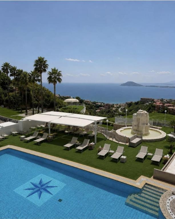 a pool with lounge chairs and a view of the ocean at Hotel Gli Dei in Pozzuoli