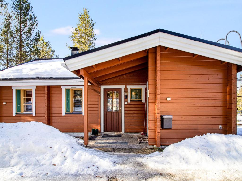 a wooden house with snow in front of it at Holiday Home Naavarinne by Interhome in Muonio