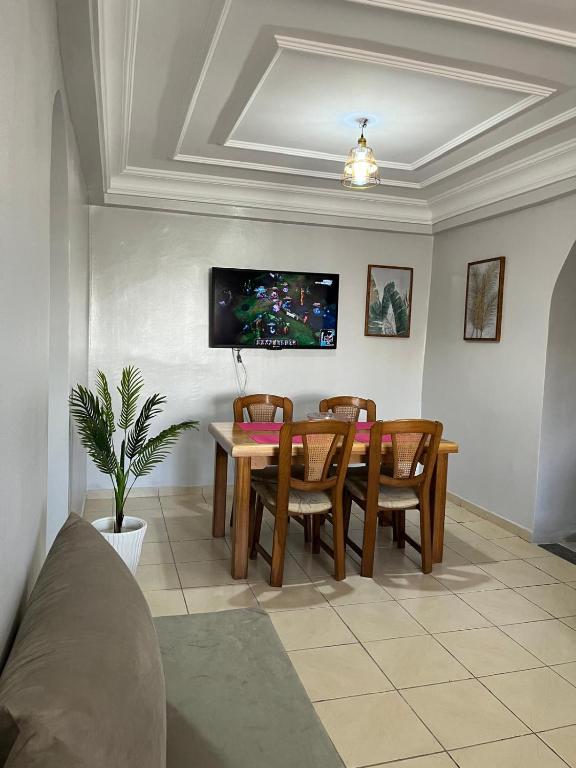 a dining room with a table and chairs and a tv at charmant appartement forêt et mer in Tangier