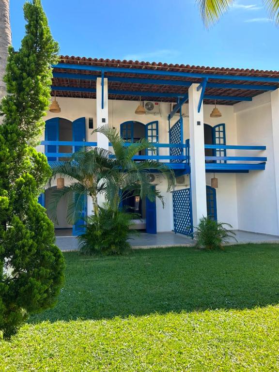 a house with blue windows and a yard at Santorini Suítes in Tamandaré