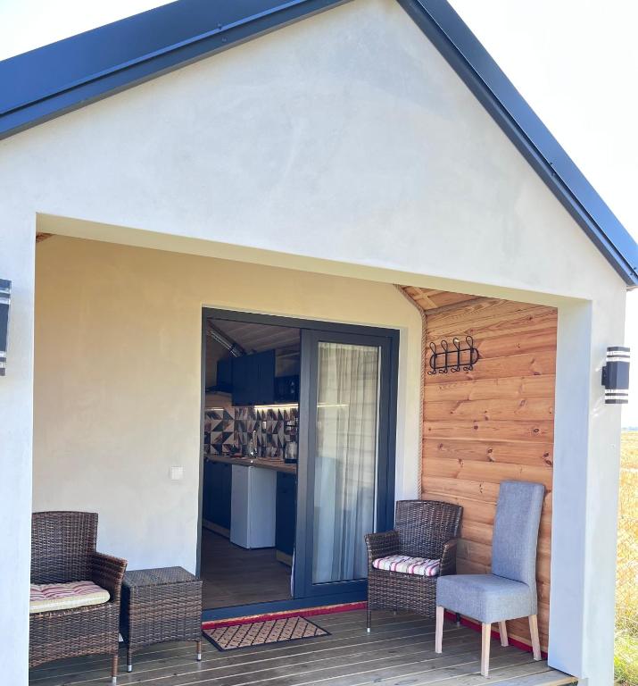 a patio with chairs and a door to a kitchen at Domek Słoneczna in Mieroszyno