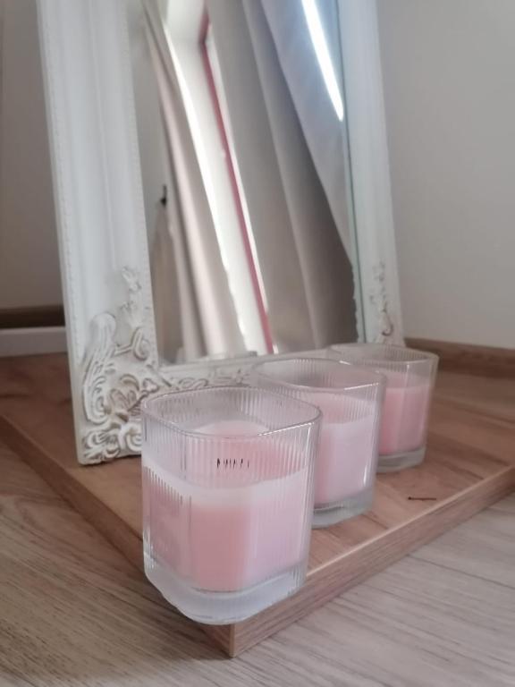 three plastic cups sitting on a wooden shelf in front of a mirror at Apartmán Nádvorie in Levoča