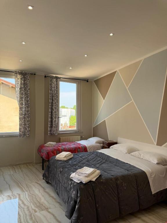 a bedroom with two beds and a large window at Rooms Vincanto in Salsomaggiore Terme