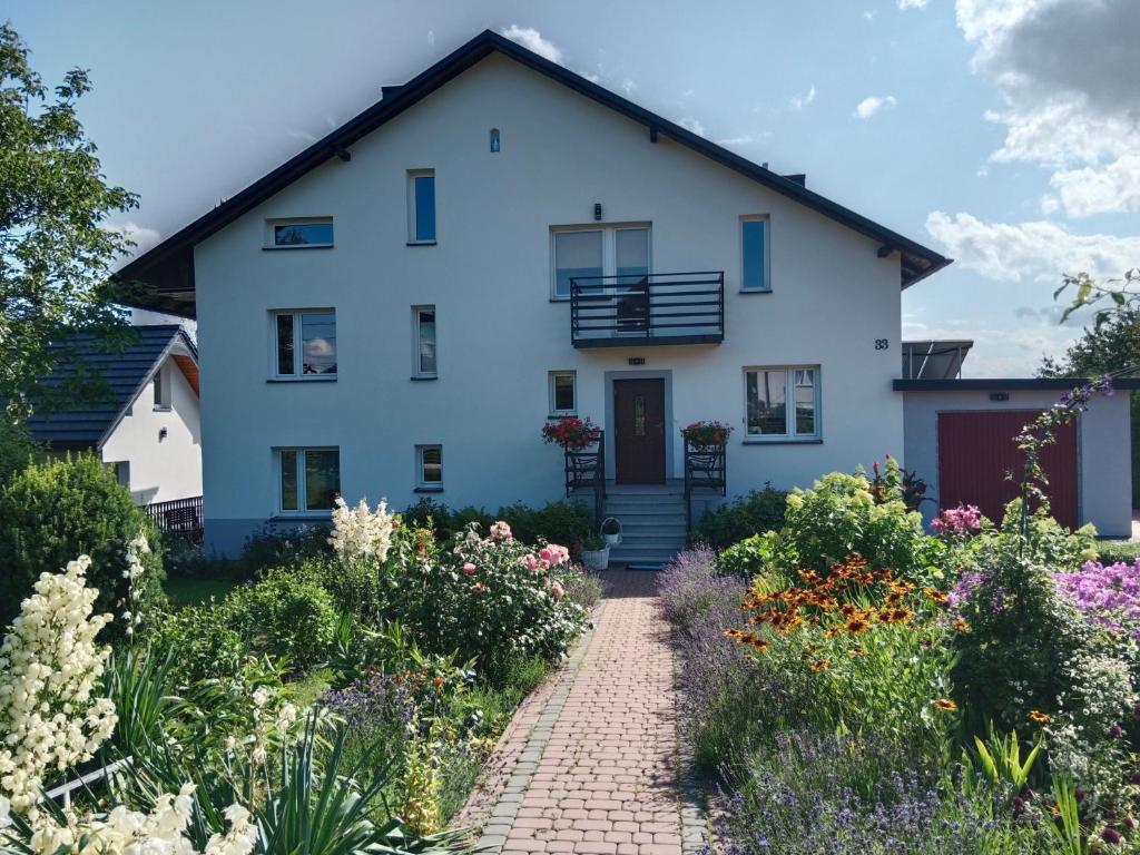 a white house with a garden in front of it at Agroturystyka u Basi in Wola Kalinowska