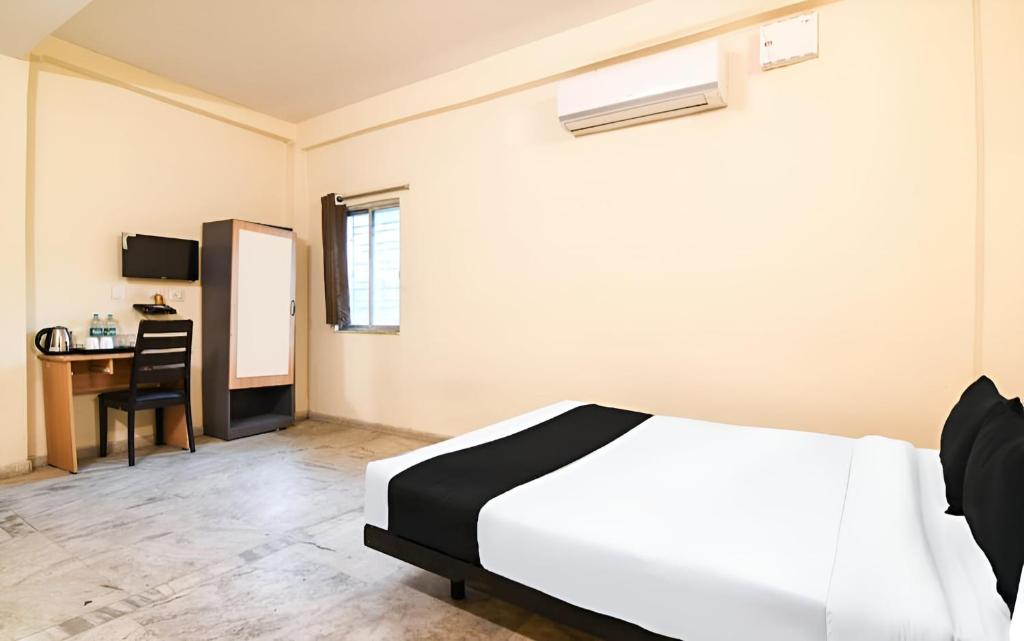 a bedroom with a bed and a desk with a chair at Super Hotel O Profulla Devi Guest House in Jojera