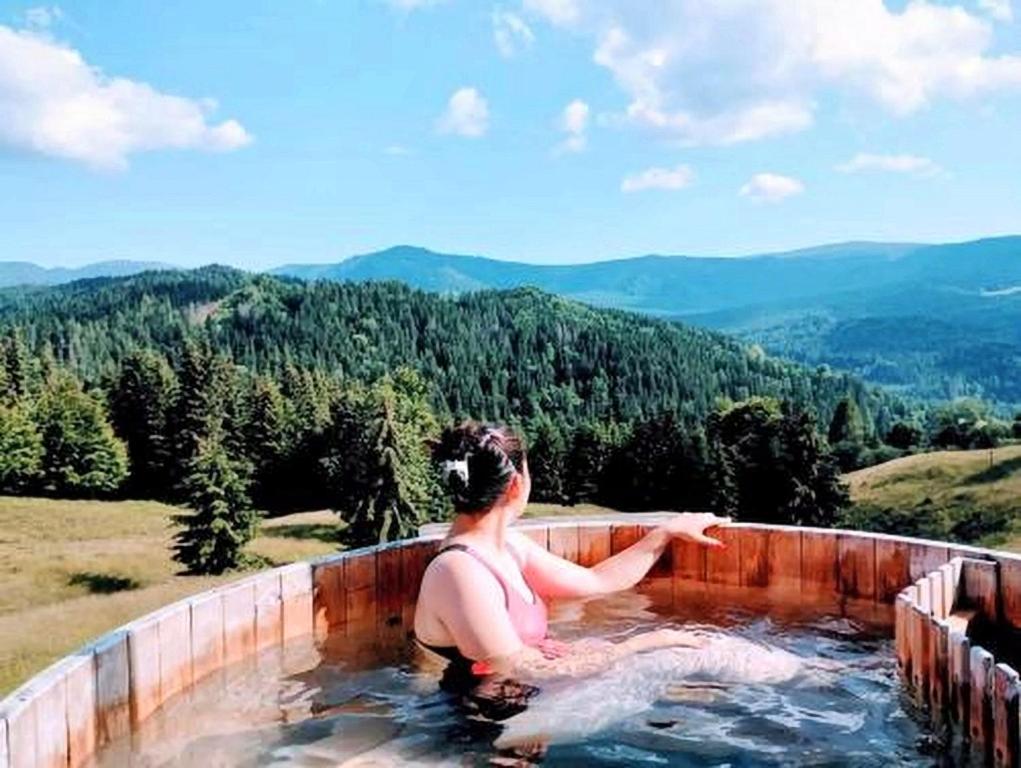 a woman sitting in a hot tub in the mountains at Domeniul Barabuc Colibita in Colibiţa