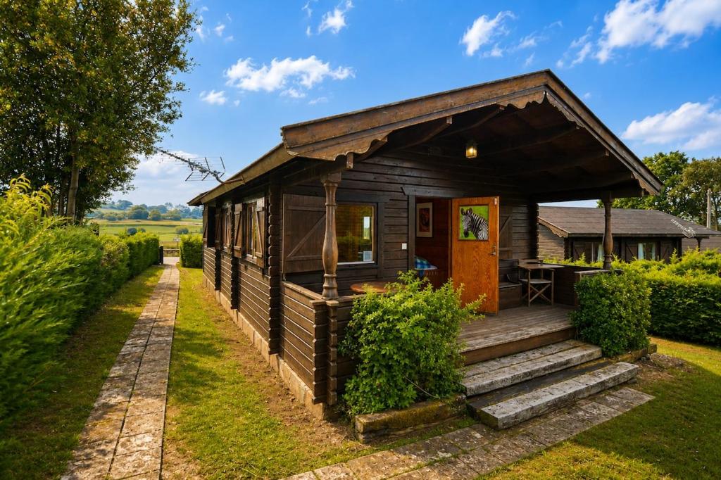 a small wooden cabin with a porch at Cabaña Las Cebras de Cabárceno in Penagos