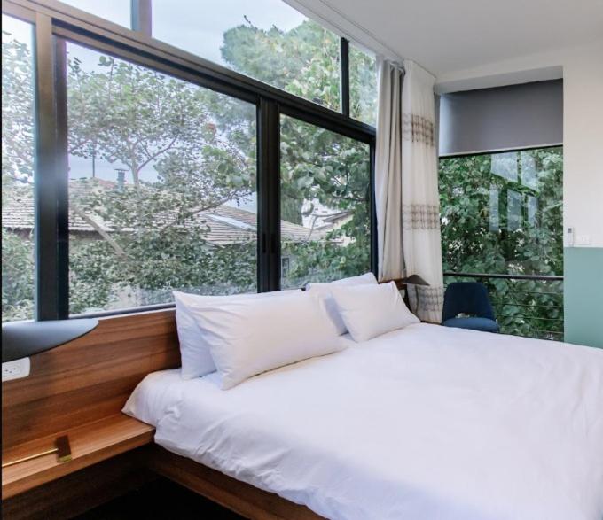 a white bed in a room with a large window at Domus Carmel Hotel in Haifa
