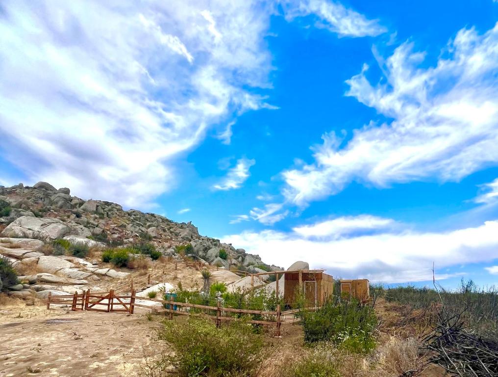 ein Zaun in einem Feld mit blauem Himmel und Wolken in der Unterkunft Solara Glamping in Tecate