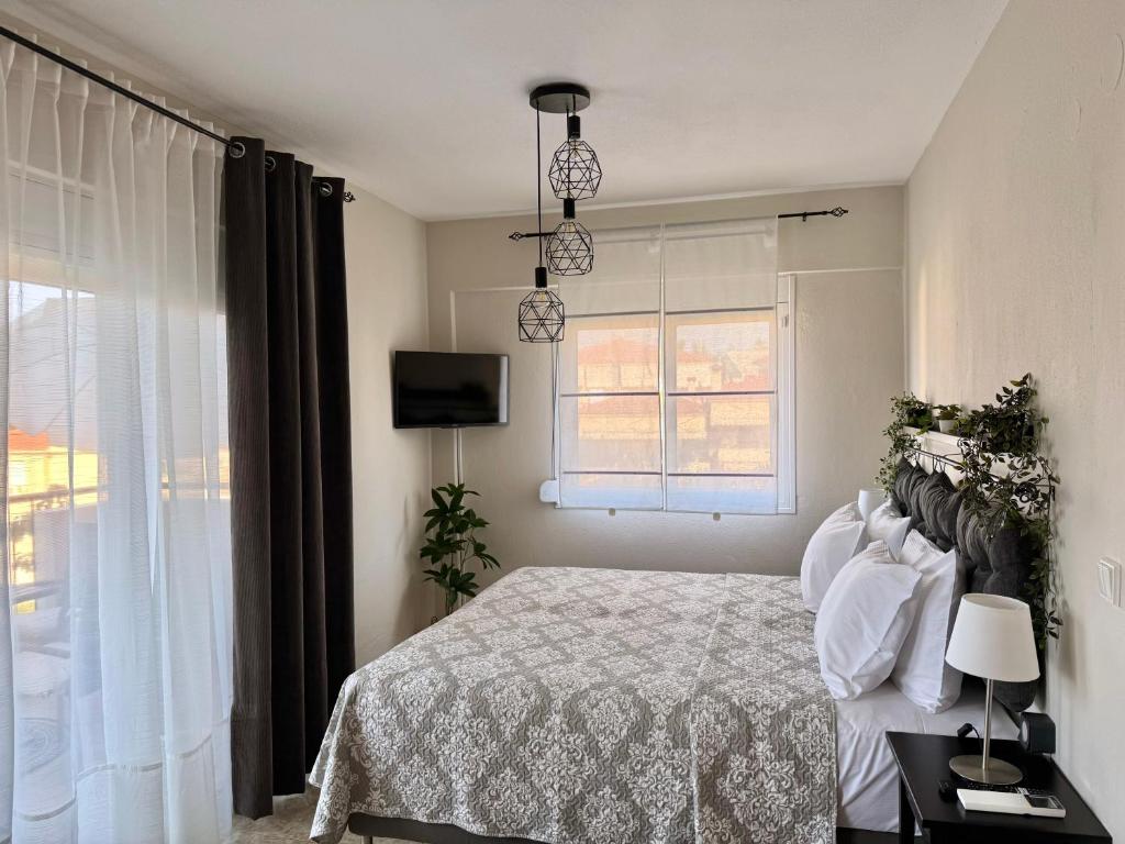 a bedroom with a bed and a tv and a window at Sun Sight - Deluxe Meridian Vista Suites in Pefkochori