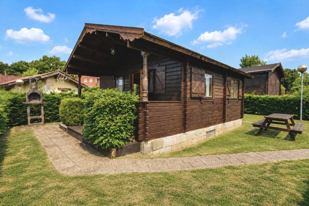 a wooden cabin with a picnic table in a yard at Cabaña Los Leones de Cabárceno in Penagos