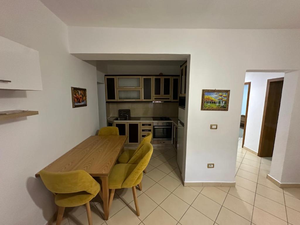 a kitchen with a wooden table and yellow chairs at Bledis Apartments in Lushnjë
