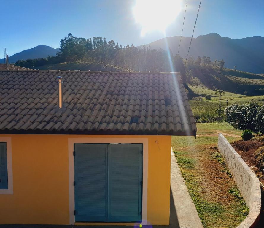 a yellow house with a blue door in a field at Recanto do Gigante Adormecido in Joanópolis