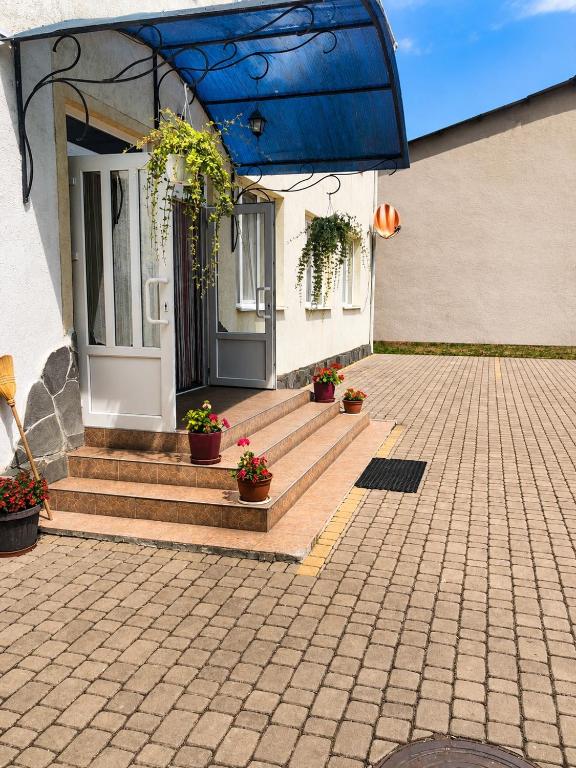 a house with a porch with potted plants on it at Hotel Marianna in Berehove