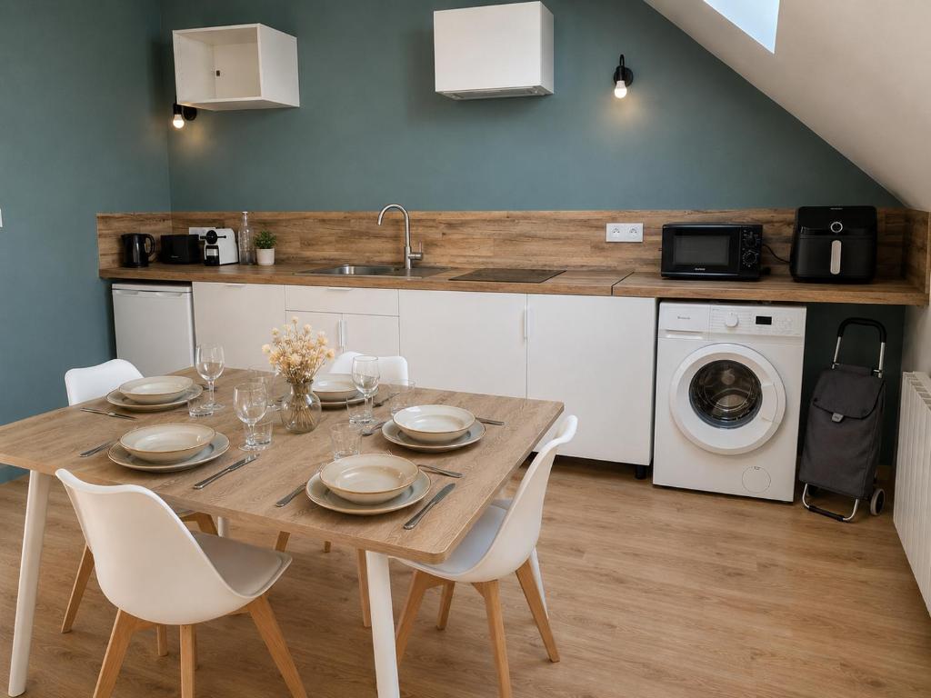 a dining room table with white chairs and a kitchen at Cap Ouest in Fécamp