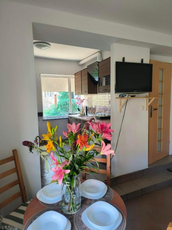 a kitchen with a table with plates and a vase of flowers at Apartament przy weneckim mostku in Kowary