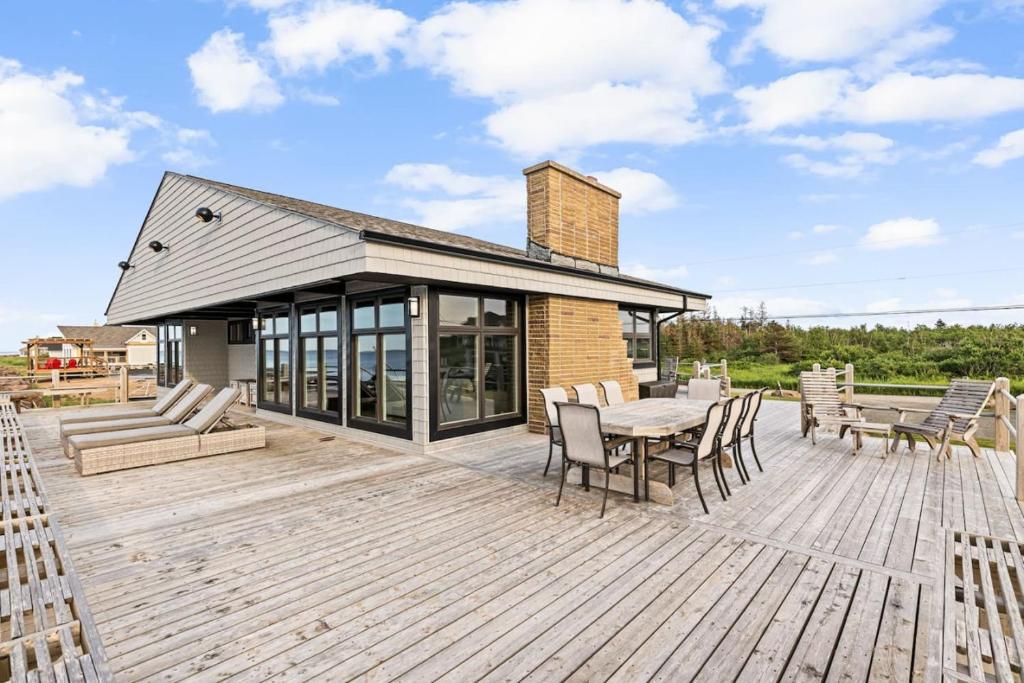 a patio with a table and chairs on a wooden deck at Ptit - 3 bedroom 2 bath Waterfront Oasis in Grand Barachois