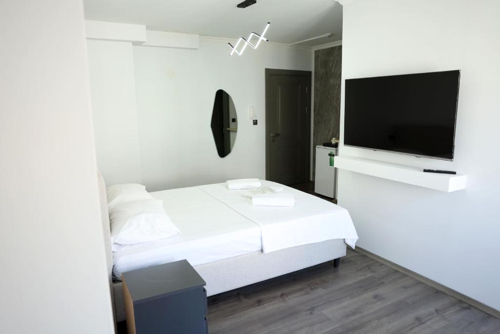 a bedroom with a white bed and a flat screen tv at Ceylan Apart Otel in Tekirdağ
