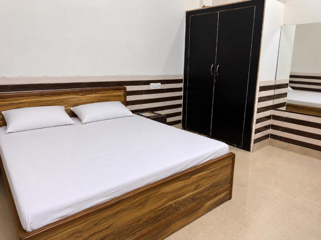 a bed with white sheets and a black cabinet at Shri Nimbark Mohini Kunj in Vrindāvan