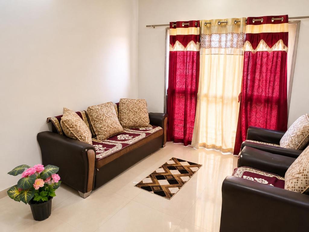 a living room with two couches and red curtains at Elite Nest Stay in Nashik