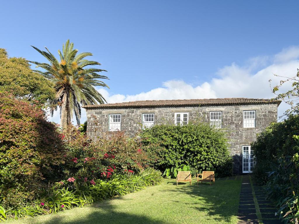 an old stone building with a palm tree and benches at Quinta das Buganvílias in Castelo Branco