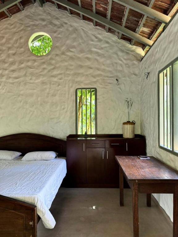 a bedroom with a bed and a table and windows at Clove Bentota in Walagedera