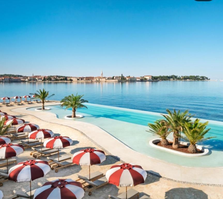 a hotel pool with umbrellas and the water at Luxury New !!! Apartment One and Only with terrace & free bikes in Poreč