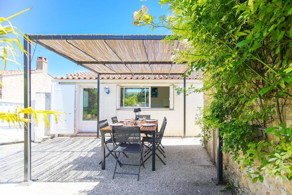 a patio with a table and chairs under a pergola at Villa Trafal - Proche plage in Saint-Michel-en-lʼHerm