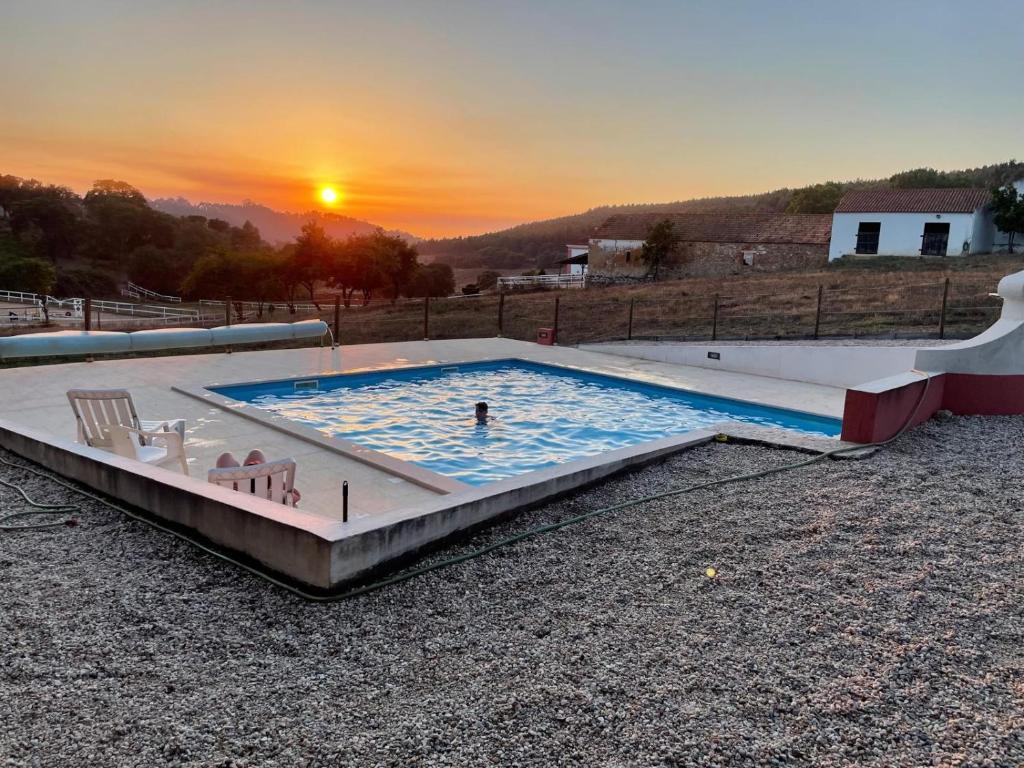 a large swimming pool with a person in the sunset at Quinta Vale Formoso in Venda da Costa