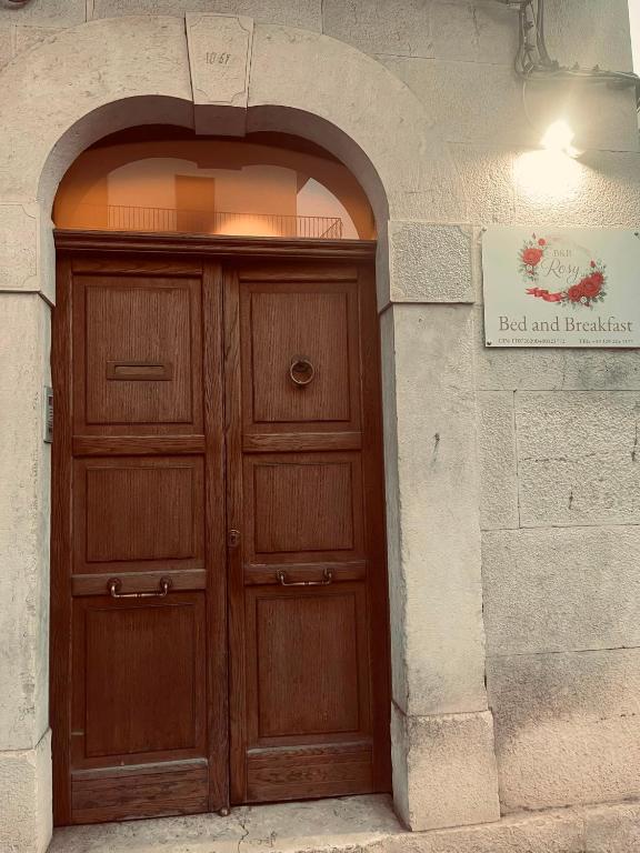 a wooden door in a stone wall with a sign at B&B Rosy in Corato
