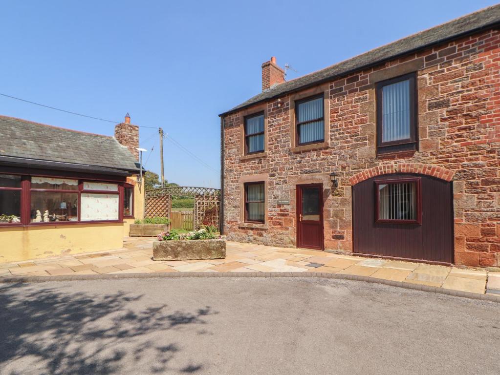 a brick house with a driveway in front of it at The Coach House in Wigton