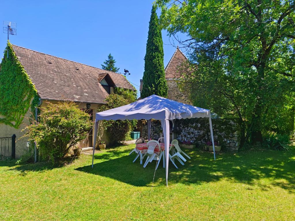 a table and chairs under a tent in a yard at Gîte - La Gariotte du Causse in Frayssinet