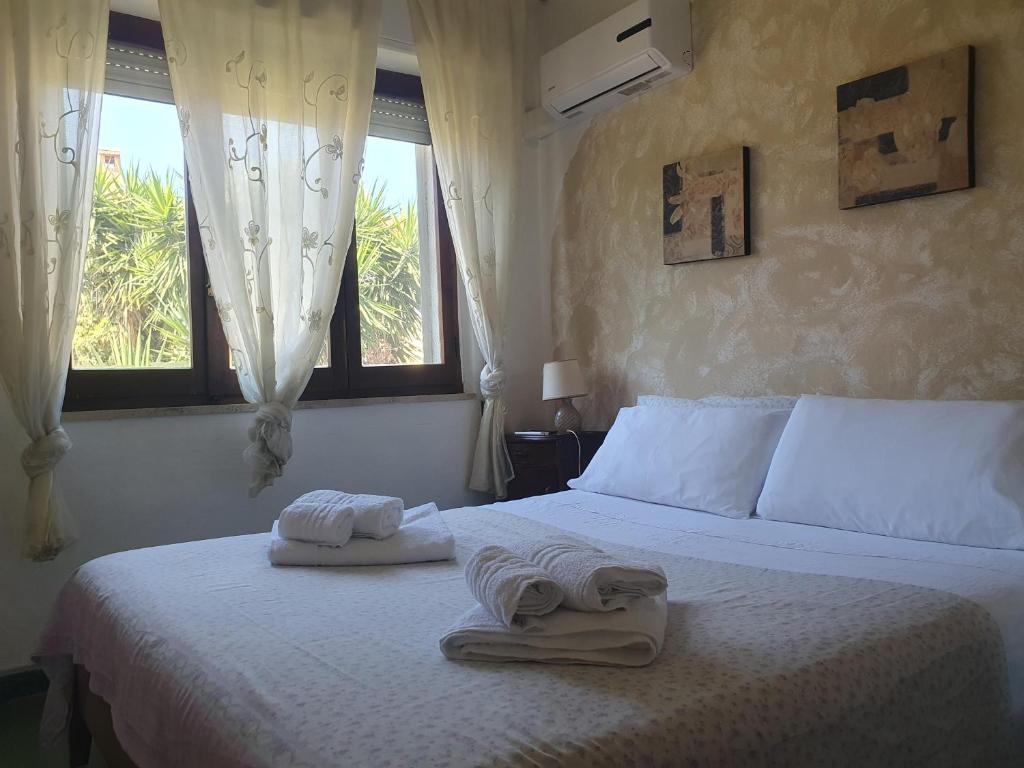 a bedroom with two towels on a bed with windows at Casa Luisa in Sarroch