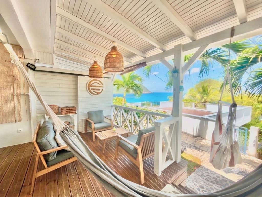 a hammock on a porch with a view of the ocean at La p’tite barque Antillaise in Deshaies