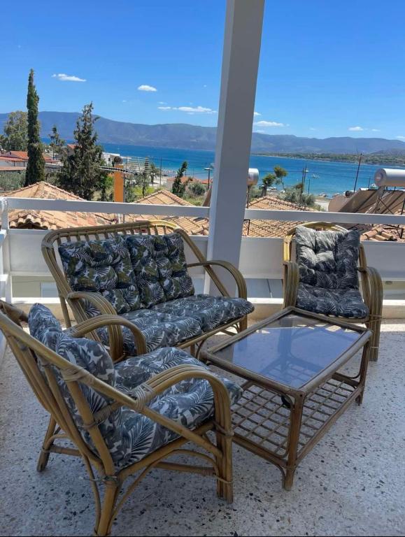 two chairs and a glass table on a porch at Maison De La Mer in Isthmia