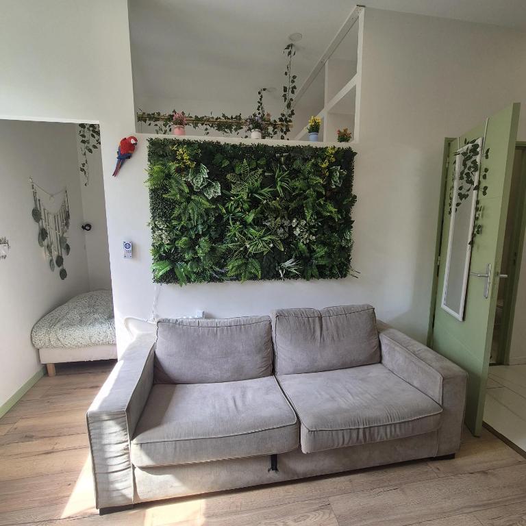 a living room with a couch and a green wall at Appartement Jungle 4 places in Saint-Étienne