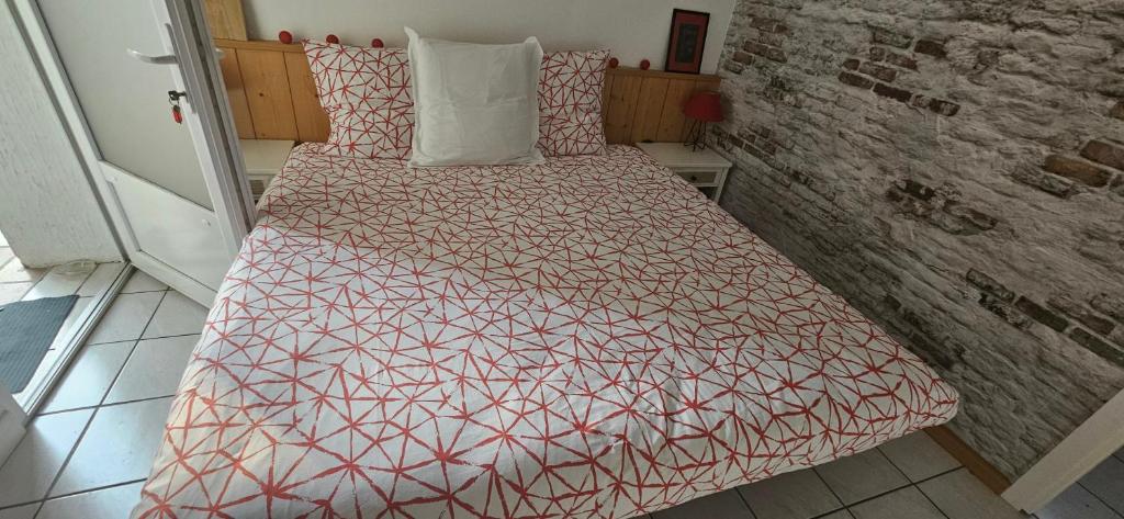 a bedroom with a bed with a red and white comforter at Les Gites D'Angres in Angres