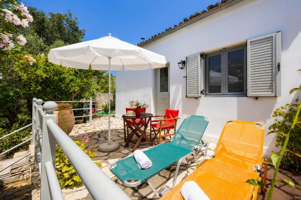a patio with a table and chairs and an umbrella at Eleni Cottage in Longós