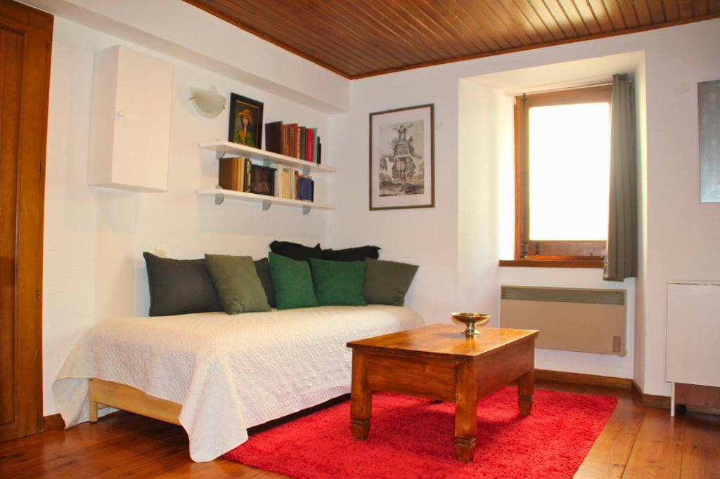 a bedroom with a bed with green pillows and a table at Apartamento-Estudio in Osséja