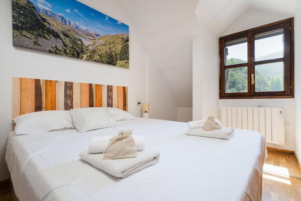 a bedroom with a large white bed with towels on it at Apto Aloha Panticosa | Piscina | WIFI | Vistas in Panticosa