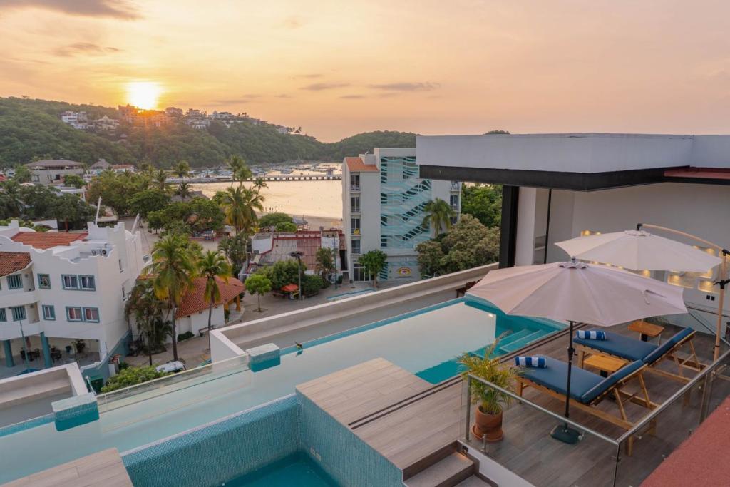 a pool with umbrellas and chairs on a building at EOS Suites in Santa Cruz Huatulco