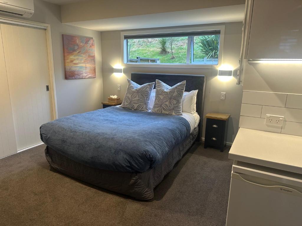 a bedroom with a bed with pillows and a window at Blue Skies Guest Accommodation in Queenstown